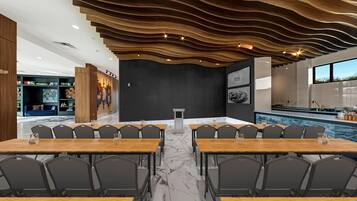 A modern dining area with marble flooring, wooden tables, and black chairs.
