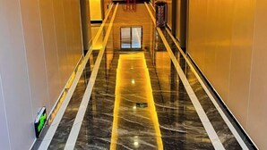 Un pasillo con piso y paredes reflectantes, que conduce a una puerta al final.