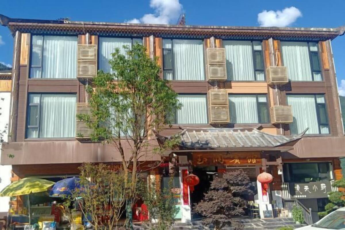 Een meerlaags gebouw met grote ramen, airconditioning en een traditionele entree met een betegeld dak.