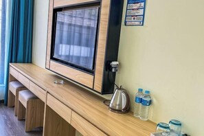 Ein Holztisch mit integriertem Fernseher, einem Wasserkocher und Wasserflaschen.