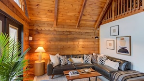 Un salon chaleureux avec un plafond en bois, un canapé en cuir noir et une petite table basse.