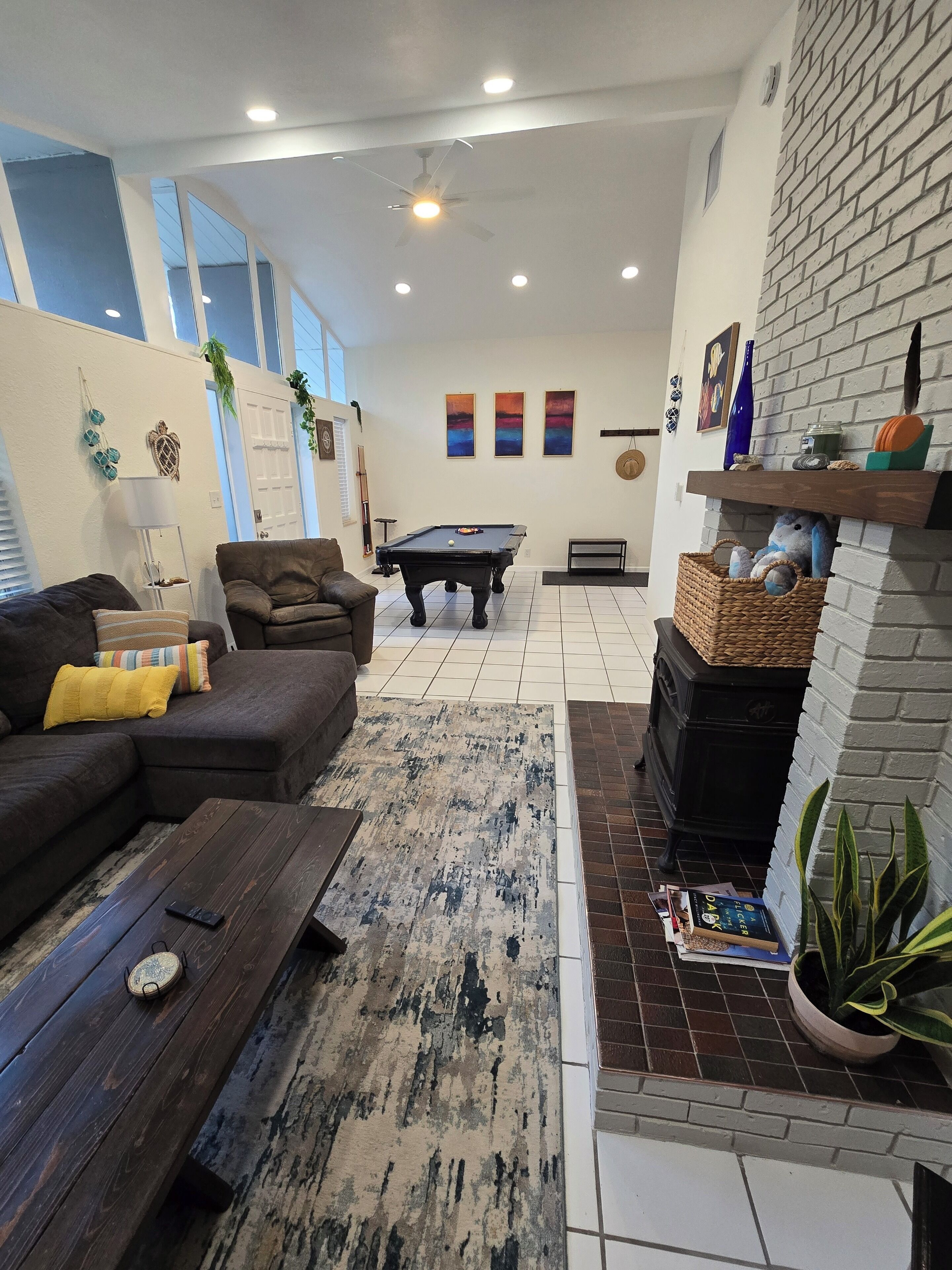 A living room with a pool table, sofas, a coffee table, and a fireplace.