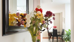 A hallway with a glass console table, a mirror, and a vase of flowers. - Elegant Surco Flat (Santiago de Surco)