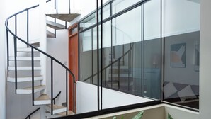 A spiral staircase with glass railings and a wooden door at the top. - Elegant Surco Flat (Santiago de Surco)