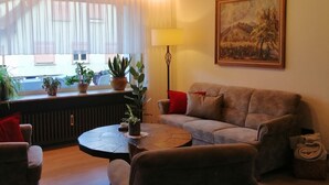 A cozy living room with a wooden ceiling, a sofa, a coffee table, and a painting on the wall. - Gemütliche, Ruhige Ferienwohnung in Waldreicher Umgebung , 30 km bis Heidelberg (Schönbrunn)