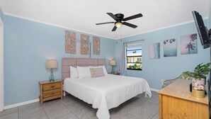 A bedroom with a bed, nightstands, a ceiling fan, artwork on the walls, and a window with a view. - Charming villa with 2 bedrooms, 4 miles from gulf beaches. Dogs welcome!  (Englewood)