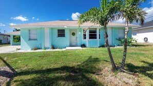 A single-story house with a light blue exterior, a front porch, and a small lawn. - Charming villa with 2 bedrooms, 4 miles from gulf beaches. Dogs welcome!  (Englewood)