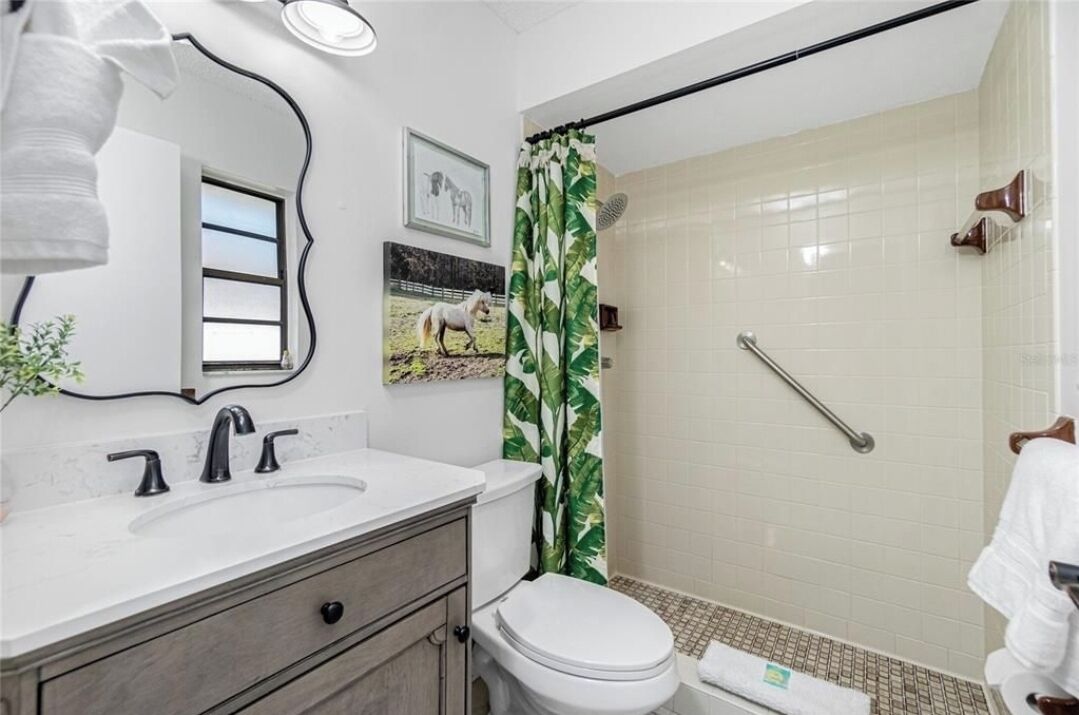 A bathroom with a white sink, a toilet, and a shower with a green curtain.