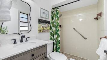 A bathroom with a white sink, a toilet, and a shower with a green curtain.