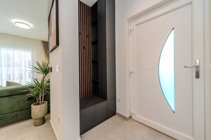 A minimalist space with a unique door, shelving unit, and a cozy sofa area.