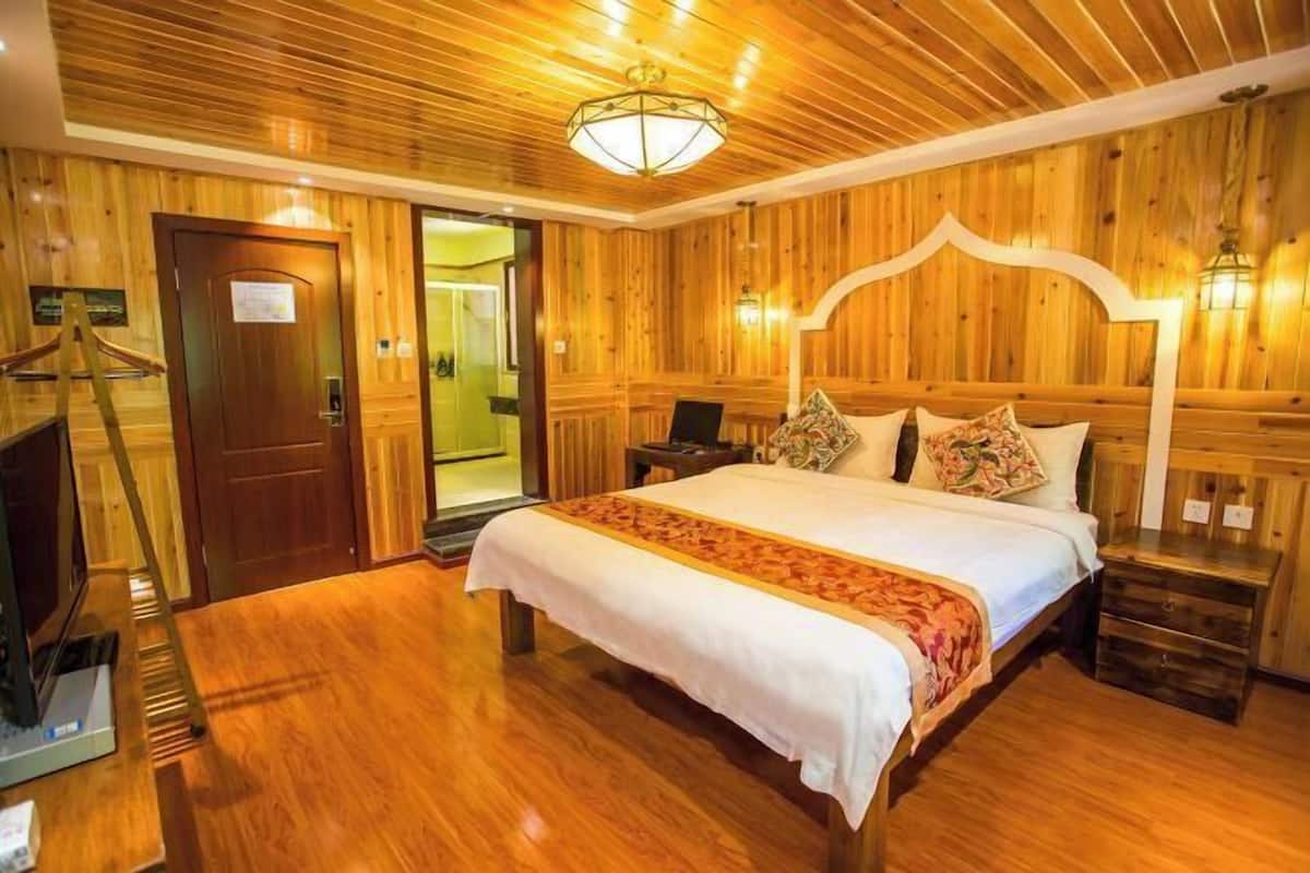 A wooden-paneled bedroom with a bed, bedside tables, a desk, and a chair.