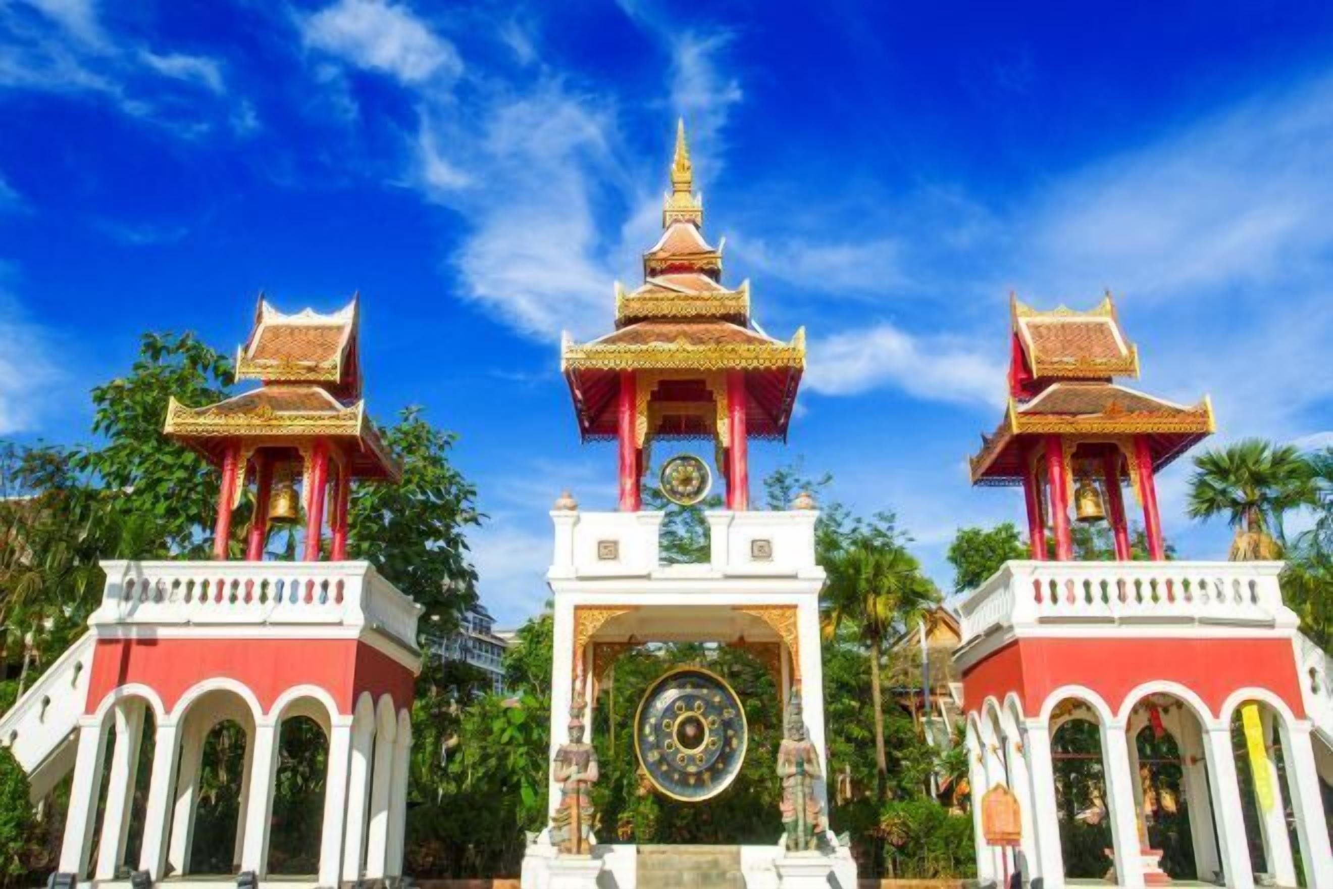 A traditional temple with a central tower and two smaller towers, surrounded by lush greenery.