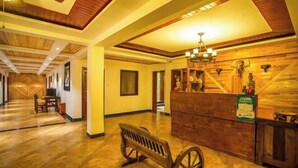A hotel lobby with a wooden reception desk, a bench, and a chandelier. - Meigonghe Inn (Jinghong)