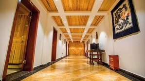 A long hallway with wooden ceiling beams and a polished floor, leading to a door at the end. - Meigonghe Inn (Jinghong)