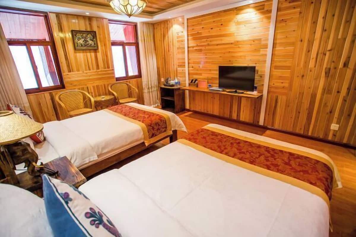 A room with two beds, a television, wooden walls, and a window.