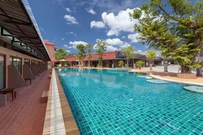A swimming pool with a tiled deck, surrounded by trees and buildings. - Naina Resort & Spa Phuket (Phuket)