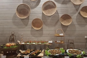 A buffet setup with various food items and decorative baskets on a wooden wall. - Naina Resort & Spa Phuket (Phuket)