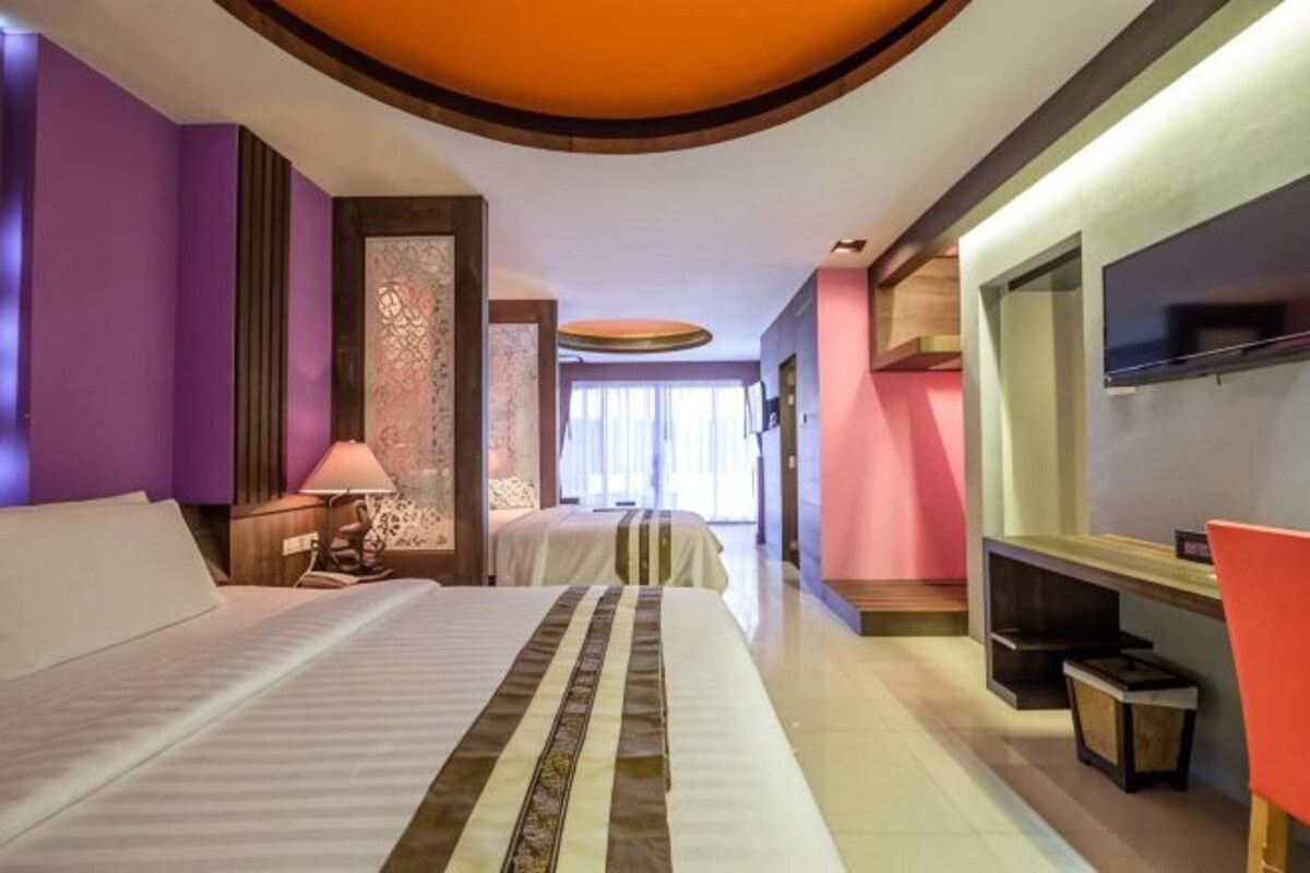 A hotel room with a bed, bedside tables, a TV, and a desk.