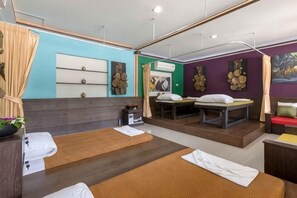 A room with two beds, a massage table, and a small table with a plant. - Naina Resort & Spa Phuket (Phuket)