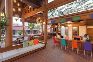 A restaurant with a high ceiling, wooden beams, and a bar area with colorful chairs. - Naina Resort & Spa Phuket (Phuket)