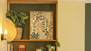 A cozy room with a bookshelf, a potted plant, and a wall-mounted light fixture. - Cocon Urban Jungle - Studio Rénové Dans le Centre Ancien (Montélimar)