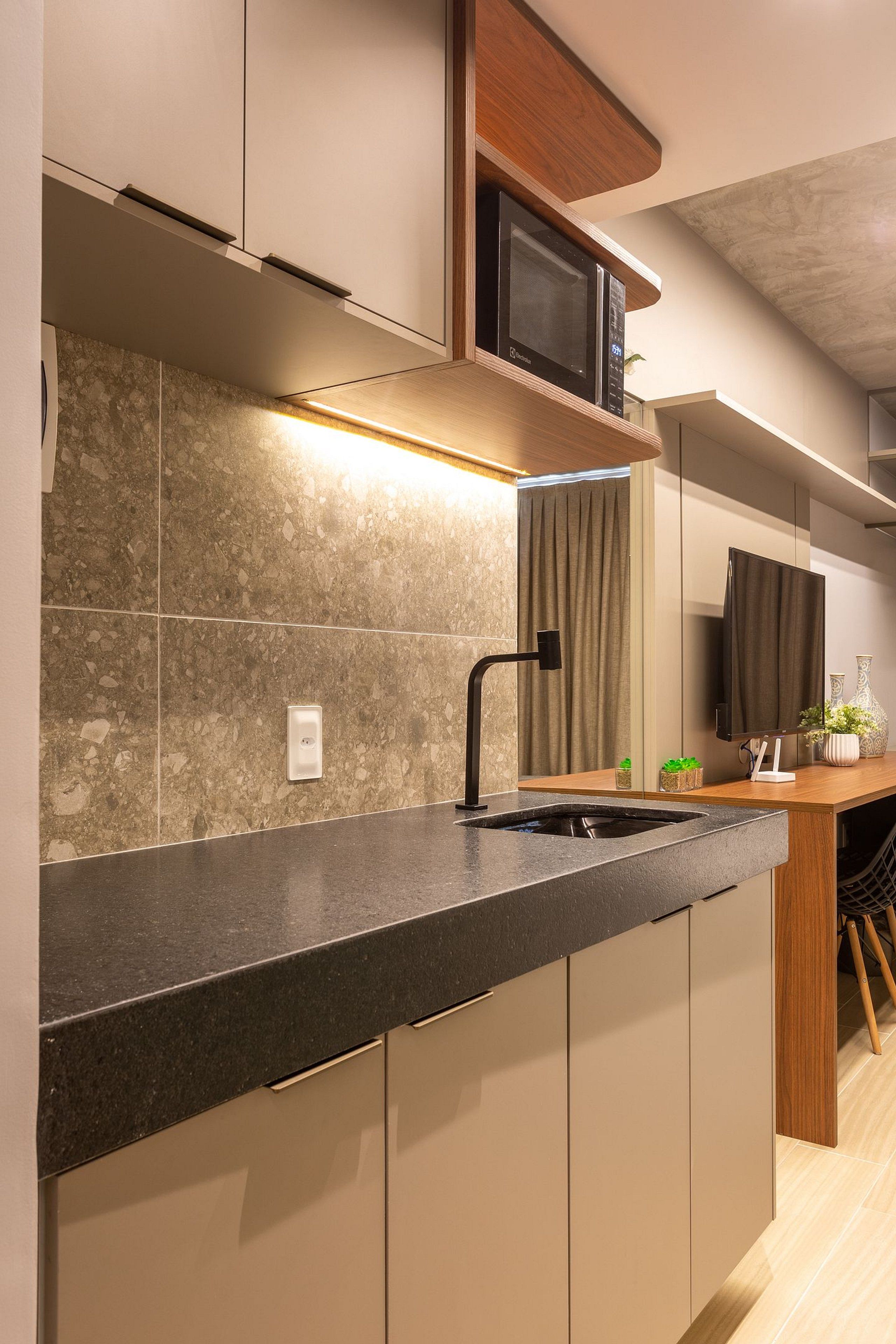 Una cocina moderna con microondas integrado, un lavamanos y una encimera de madera.
