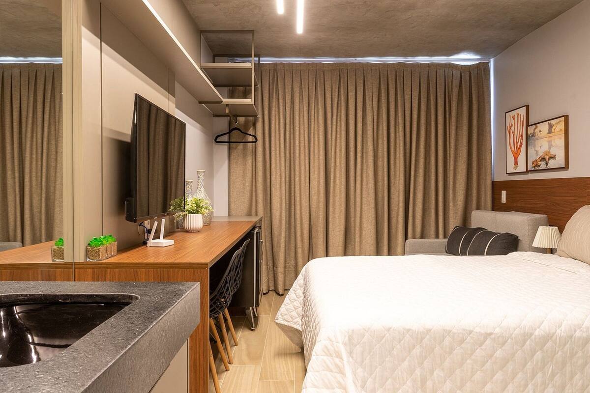 A modern hotel room with a bed, a desk, a TV, and a bathroom.
