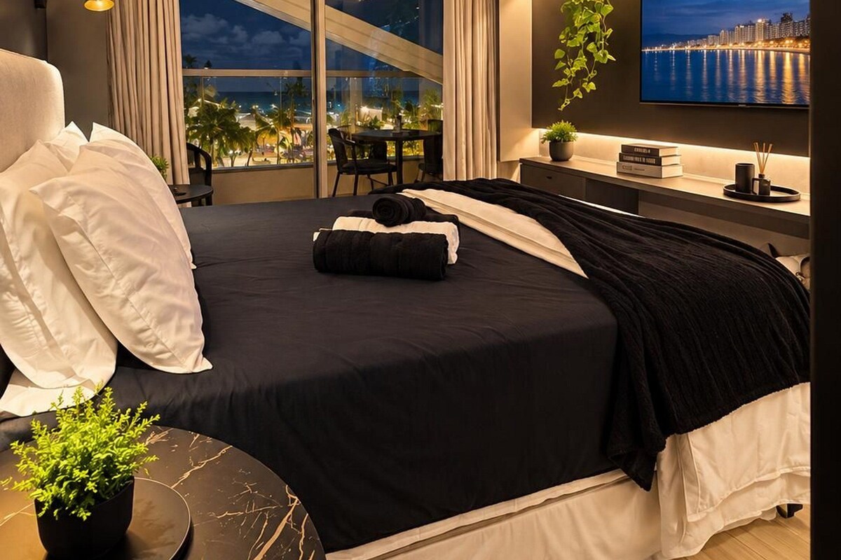 Une chambre d’hôtel moderne dotée d’un grand lit, d’une télévision, d’un bureau et d’un balcon offrant une vue sur la ville.
