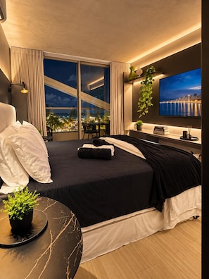 Une chambre d’hôtel moderne dotée d’un grand lit, d’une télévision, d’un bureau et d’un balcon offrant une vue sur la ville.