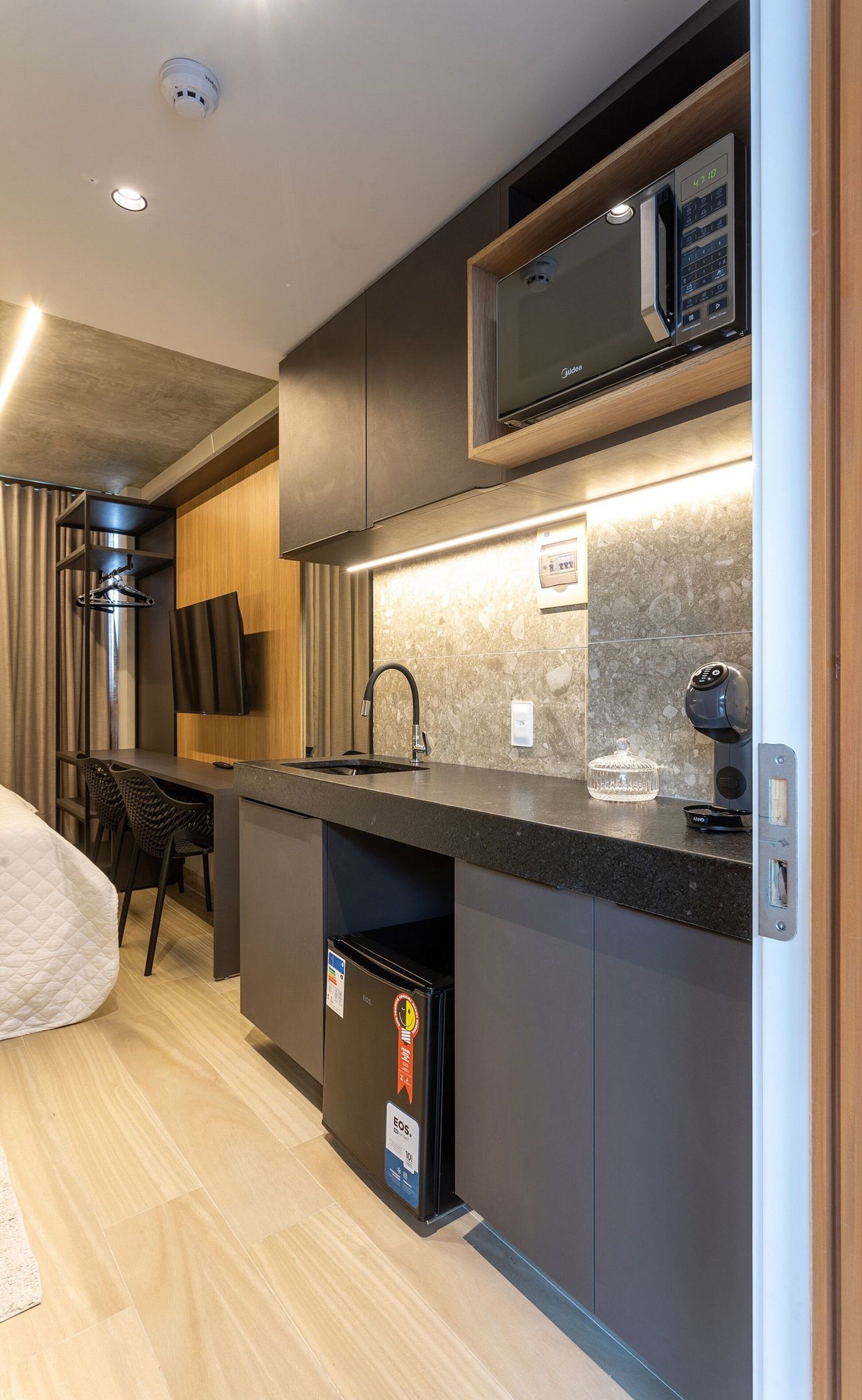 A modern kitchen with a built-in microwave, a sink, and a trash bin.