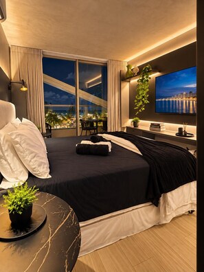 Une chambre d’hôtel moderne dotée d’un grand lit, d’une télévision, d’un bureau et d’un balcon offrant une vue sur la ville.