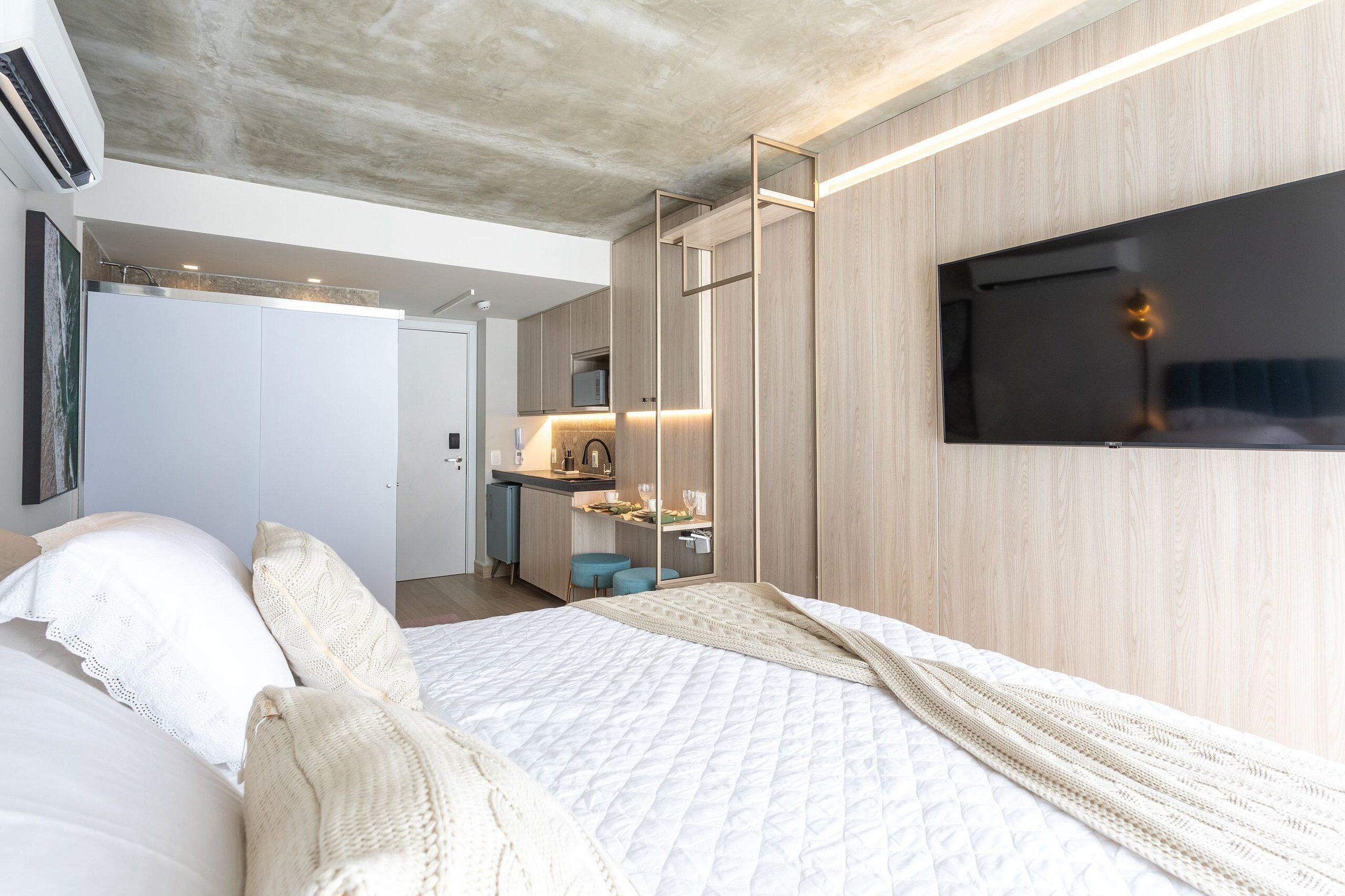 Een moderne slaapkamer met een bed, een televisie en een kitchenette.