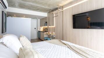 Een moderne slaapkamer met een bed, een televisie en een kitchenette.