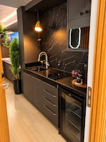 Cozinha moderna com painel de mármore preto, eletrodomésticos de aço inoxidável e forno embutido.