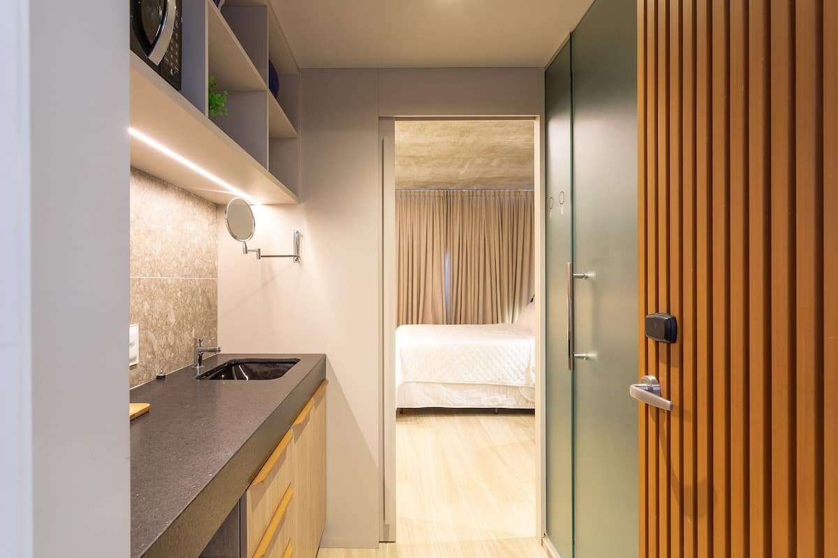 A compact hotel room with a kitchenette, a bed, and a sliding door closet.