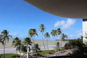 Vista da praia com palmeiras e céu claro.