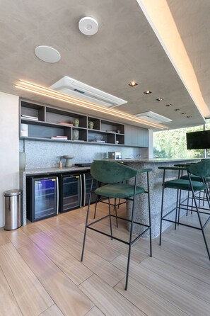 Une cuisine moderne avec des tabourets de bar, des étagères intégrées et une grande fenêtre.