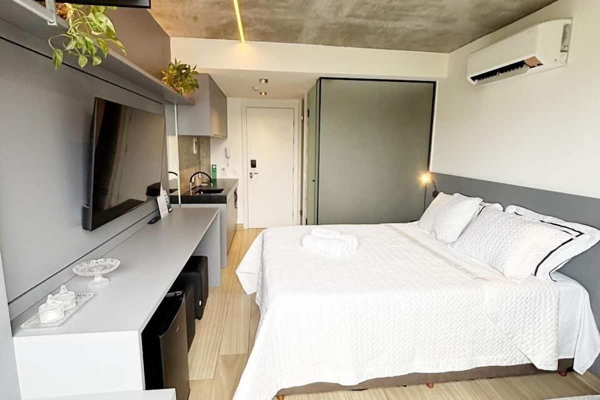 A modern bedroom with a bed, bedside table, and a TV.