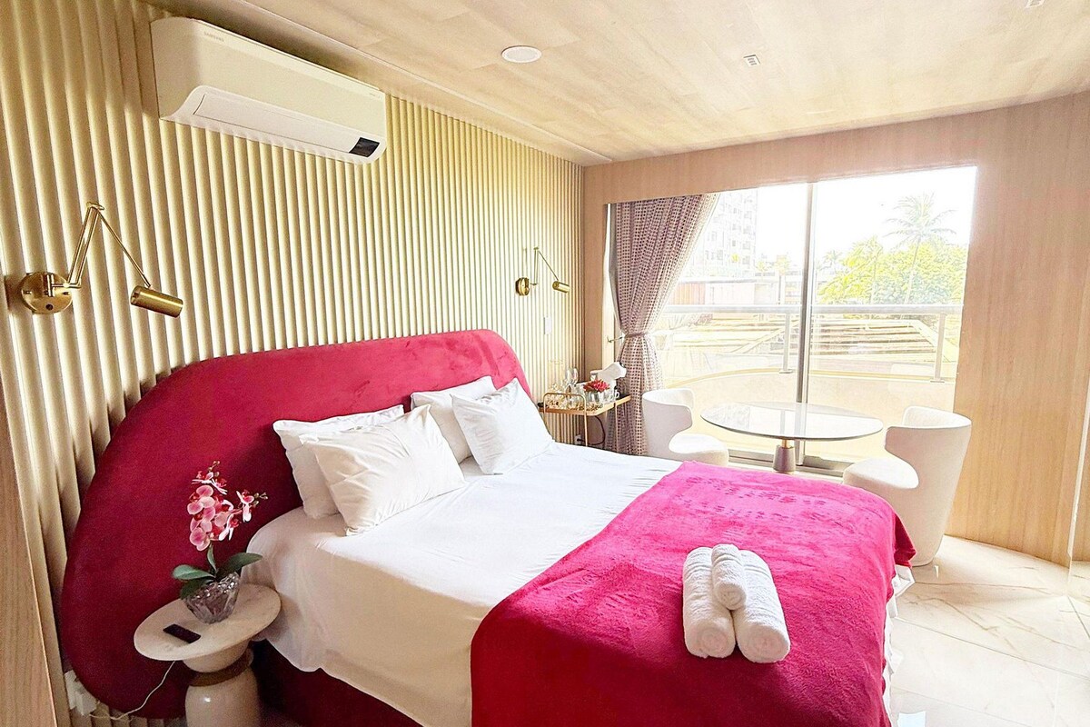 Une chambre d’hôtel avec un grand lit, une table de chevet, une petite table avec des chaises et une fenêtre avec des rideaux.