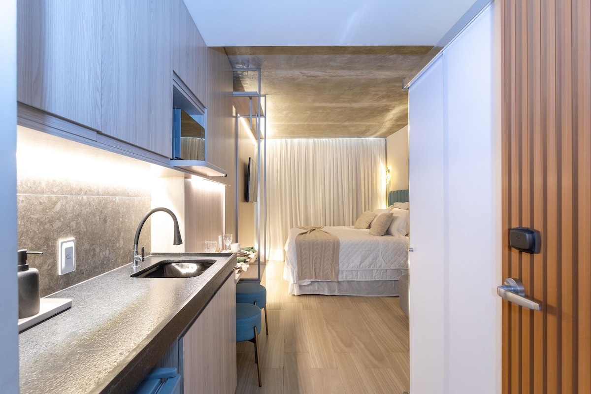 Une petite pièce comprenant un coin cuisine, un lit et une porte.