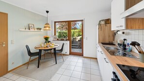Cocina compacta con comedor, horno empotrado y lavamanos.