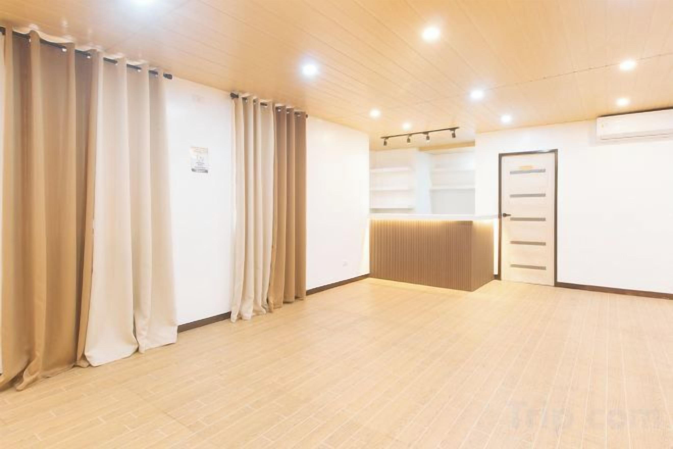 A hotel room with a wooden floor, a reception desk, and a door with a handle.