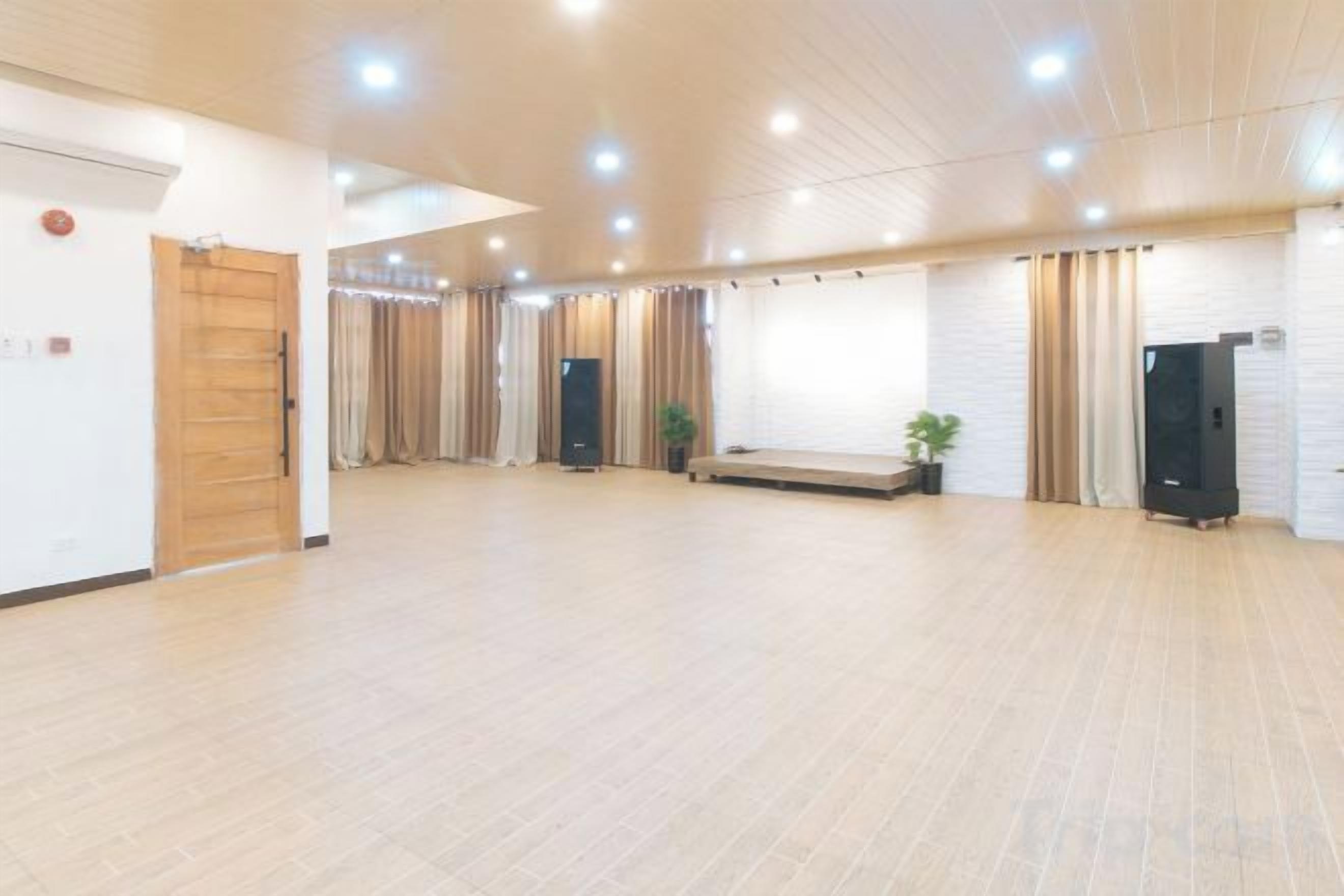 A spacious room with a wooden floor, a bench, a plant, and a black cabinet.