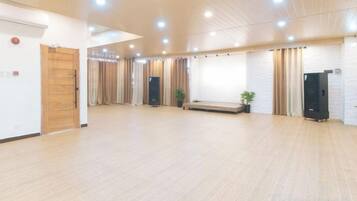 A spacious room with a wooden floor, a bench, a plant, and a black cabinet.