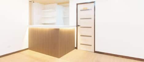 A reception area with a wooden reception desk, a white wall, and a door.