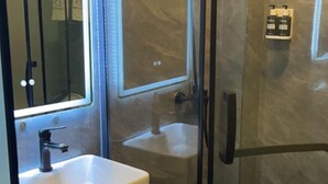 Un bagno con doccia vetrata, lavandino e specchio.