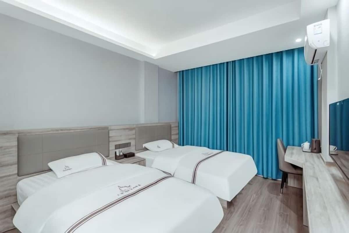 A hotel room with two beds, a desk, and a chair.