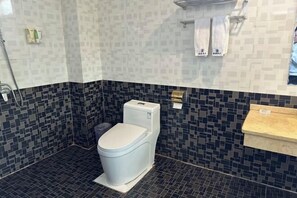 A modern bathroom with a white toilet, dark mosaic tiles, and a beige countertop. - Jiahao Meisu Hotel (Guilin Jinshan Square) (Guilin)