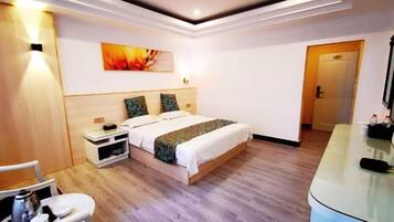 Een moderne hotelkamer met een houten vloer, een bed met beddengoed met een patroon, een nachtkastje met een lamp en een schilderij aan de muur.
