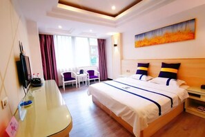 A hotel room with a bed, a desk, a chair, and a painting on the wall.